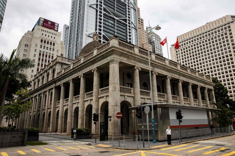 A man (bottom R) waits at a traffic light outside the Court of Final Appeal in Hong Kong on March 31, 2022. - Australian and Canadian judges confirmed on March 31 they will stay on Hong Kong's top court after two senior British judges resigned to avoid endorsing China's crackdown on political freedoms in the financial hub. (Photo by ISAAC LAWRENCE / AFP) (Photo by ISAAC LAWRENCE/AFP via Getty Images)