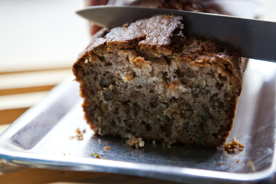 A knife cutting into a loaf of banana bread.