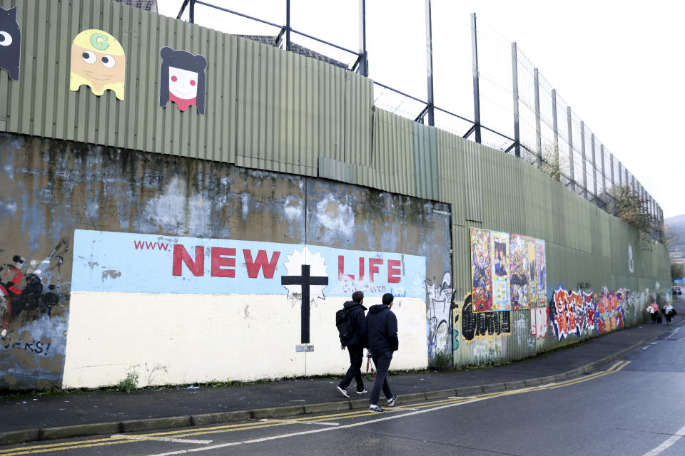 Tourists walk by the peace wall, in west Belfast, Northern Ireland, Saturday, Jan. 28, 2023. Twenty-five years ago, the Good Friday Agreement halted much of the violence of Northern Ireland’s Troubles. Today, grassroots faith leaders are trying to build on that opportunity. They're working toward reconciliation in a land where religion was often part of the problem. (AP Photo/Peter Morrison)