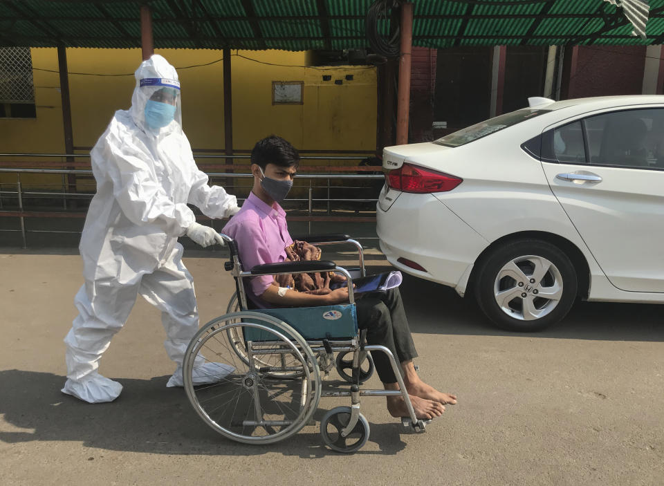 A medical staff in a protective outfit pushes a patient on a wheel chair at a government hospital in Prayagraj, India, Thursday, Nov.5, 2020. With 8.3 million confirmed cases of coronavirus, India is the second worst-hit country behind the United States. (AP Photo/Rajesh Kumar Singh)