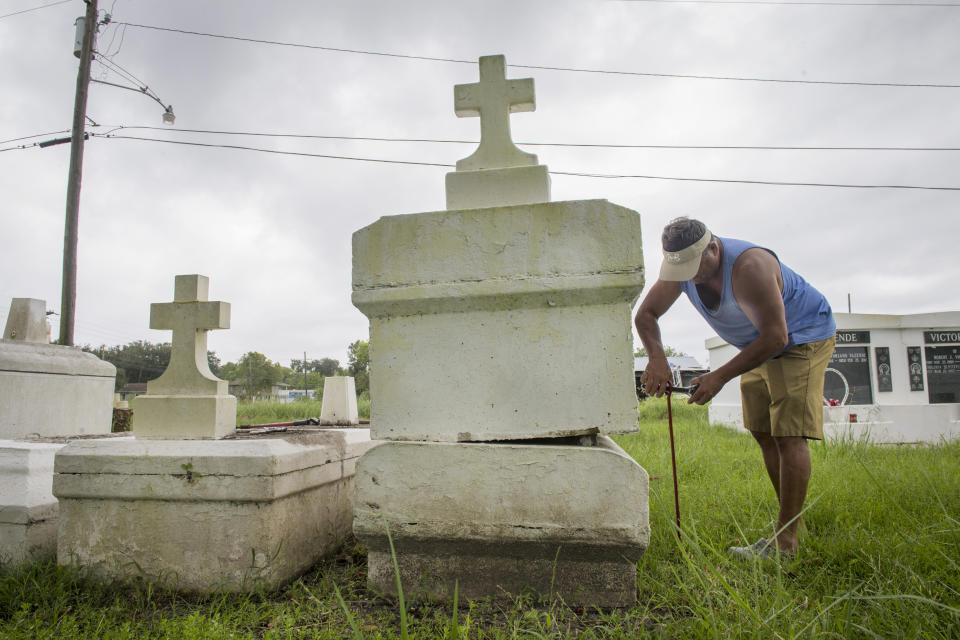 Jerry Parria uses steel cable and metal anchors to tie down four tombs belonging to his grandparents and uncles in a small cemetery near Lafitte, La., as residents along the Louisiana coast prepare for two tropical storms, Monday, Aug. 24, 2020. Parria said the tombs floated away during a previous hurricane. (Chris Granger/The Times-Picayune/The New Orleans Advocate via AP)