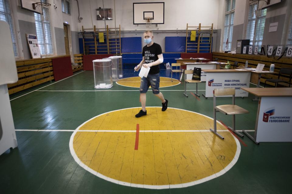 FILE - In this June 25, 2020, a voter wearing a face mask to protect against the coronavirus holds his ballot at a polling station in a school building in Moscow, Russia. Russian President Vladimir Putin is just a step away from bringing about the constitutional changes that would allow him to extend his rule until 2036. The vote that would reset the clock on Putin’s tenure in office and allow him to serve two more six-year terms is set to wrap up Wednesday, July 1, 2020. (AP Photo/Alexander Zemlianichenko, File)