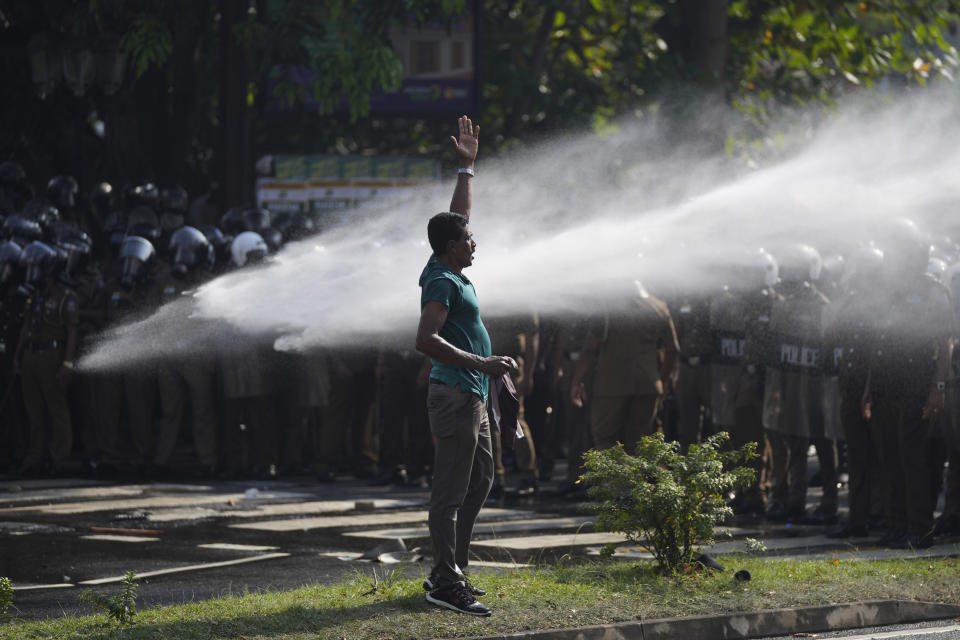 A supporter of Sri Lanka's main opposition shouts slogans as police fire water cannons to disperse them during a protest rally against high taxes and increases in electricity and fuel charges, in Colombo, Sri Lanka, Tuesday, Jan. 30, 2024. (AP Photo/Eranga Jayawardena)