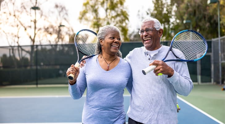 A retired couple embraces after playing tennis one morning. 