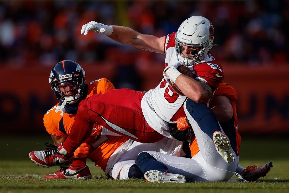 Dec 18, 2022; Denver, Colorado, USA; Arizona Cardinals tight end Trey McBride (85) is tackled by Denver Broncos linebacker Alex Singleton (49) and cornerback Pat Surtain II (2) in the second quarter at Empower Field at Mile High.