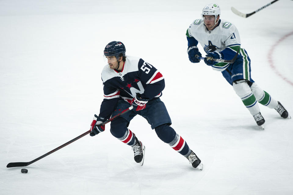 Washington Capitals defenseman Trevor van Riemsdyk (57) moves the puck past Vancouver Canucks left wing Nils Hoglander (21) during the first period of an NHL hockey game against the Vancouver Canucks, Sunday, Jan. 16, 2022, in Washington. (AP Photo/Al Drago)