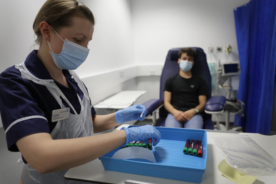 Clinical Research Nurse Aneta Gupta labels blood samples from volunteer Yash during the Imperial College vaccine trial, at a clinic in London, Wednesday, Aug. 5, 2020. Scientists at Imperial College London are immunizing hundreds of people with an experimental coronavirus vaccine in an early trial after seeing no worrying safety problems in a small number vaccinated so far. (AP Photo/Kirsty Wigglesworth)