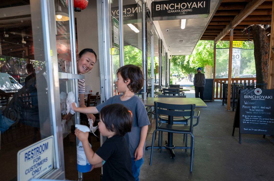 Toki Sawada, Binchoyaki chef and owner, gets some help at the restaurant as her children, Yoshi, 3, left, and Haru Takehara, 5, clean the glass door Wednesday. She said she often jokes with her restaurant industry friends, “if you ever need a dishwasher, I’ve got three!”