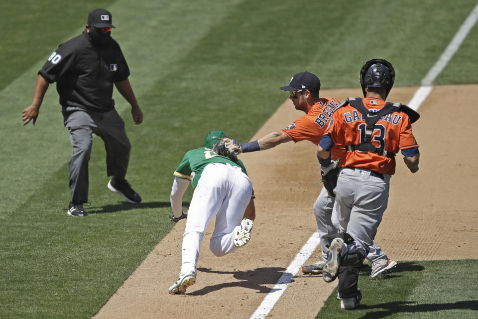 Houston Astros' Alex Bregman, second from right, tags out Oakland Athletics' Mark Canha during a rundown between third and home during the sixth inning of a baseball game Saturday, Aug. 8, 2020, in Oakland, Calif. (AP Photo/Ben Margot)