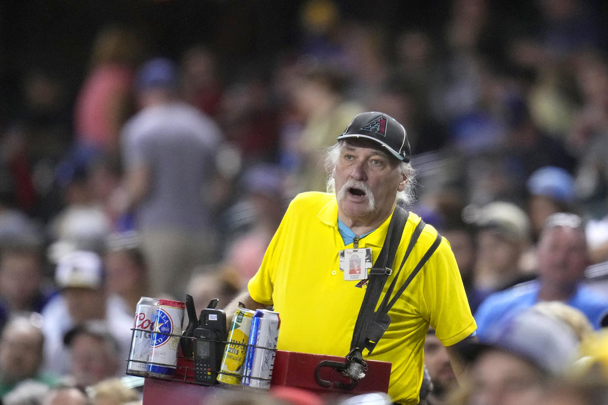 A beer vendor walks through the stands during the seventh inning of a baseball game between the Arizona Diamondbacks and the Milwaukee Brewers Tuesday, April 11, 2023, in Phoenix. (AP Photo/Ross D. Franklin)