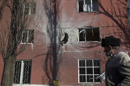 A man walks past a house damaged by fighting in the town of Vuhlehirsk near Debaltseve February 18, 2015. REUTERS/Baz Ratner