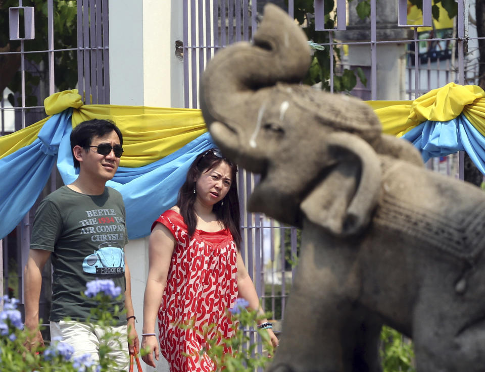 In this March 30, 2014 photo, a couple of Chinese tourists walks past a stone carving elephant as they enter for a tour at Chiang Mai University in Chiang Mai province, northern Thailand. The bucolic, once laid-back campus of one of Thailand’s top universities is under a security clampdown. Not against a terrorist threat, but against Chinese tourists. Thousands have clambered aboard student buses at the university, made a mess in cafeterias and sneaked into classes to attend lectures. Someone even pitched a tent by a picturesque lake. The reason: “Lost in Thailand,” 2012 slapstick comedy partly shot on campus that is China’s highest-grossing homegrown movie ever. (AP Photo/Apichart Weerawong)