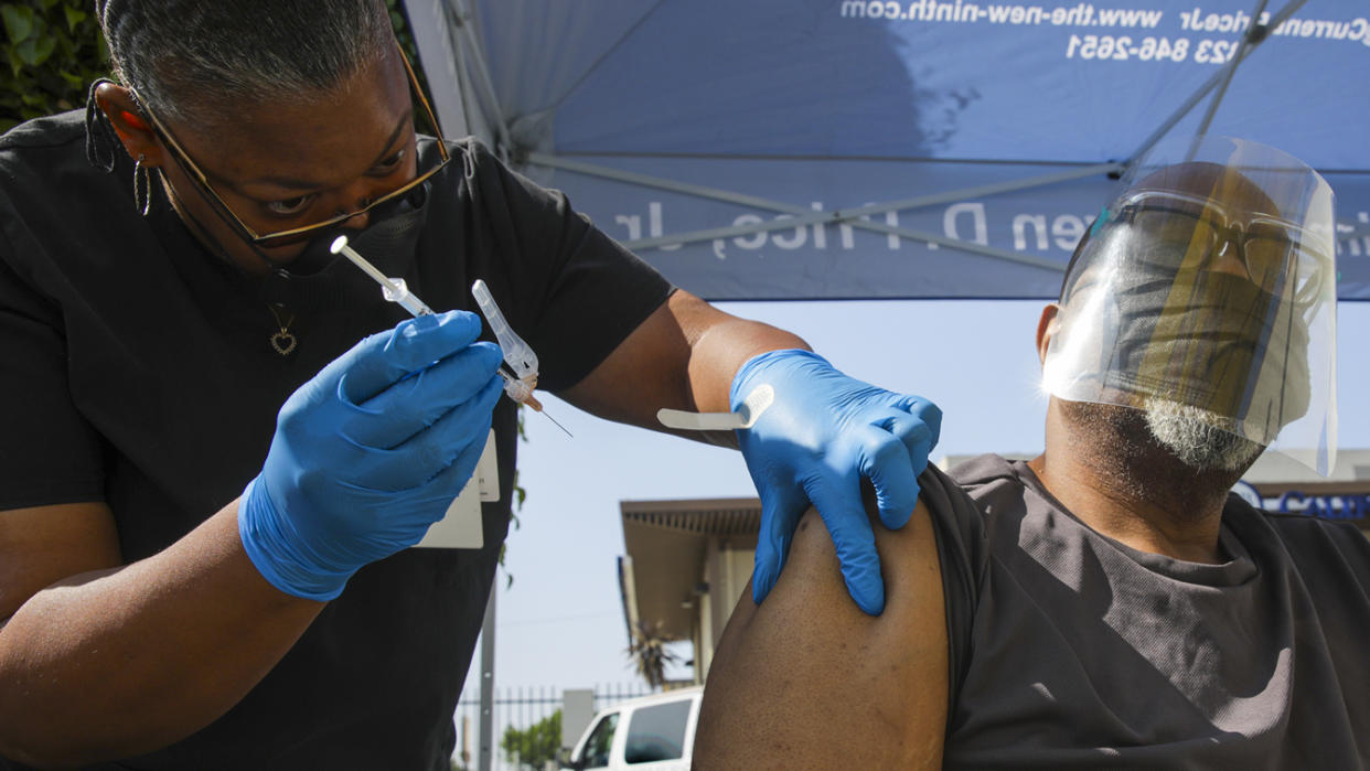Eon Walk, left, administers a Pfizer-BioNTech vaccine to Daryl Black at a mobile COVID-19 vaccine clinic, hosted by Mothers In Action in collaboration with L.A. County Department of Public Health at Mothers in Action on Friday, July 16, 2021 in Los Angeles, CA. (Irfan Khan/Los Angeles Times via Getty Images)
