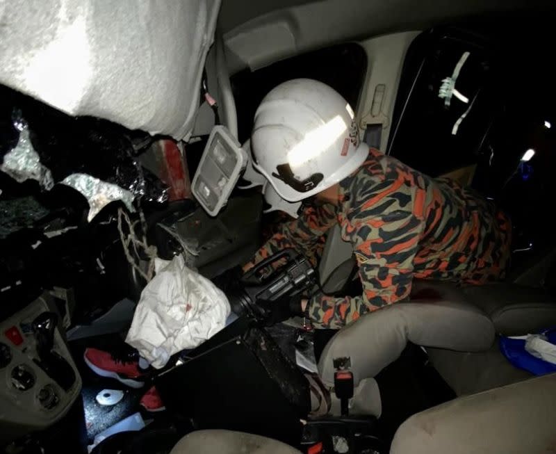 A Fire and Rescue Dept personnel attempts to extract victims from the wreckage following an accident involving a motorcycle, lorry and three cars along the North-South Expressway last night. — Picture courtesy of the Johor Fire and Rescue Department