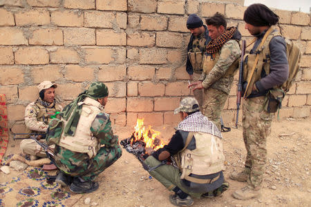 Members of the Lions of the Tigris, a group of Sunni Arab fighters and part of the Hashid Shaabi (Popular Mobilization Comimittee) warm themselves near a fire during a pasue in a military operation against Islamic State militants in Shayyalah al-Imam, Iraq November 30, 2016. REUTERS/Thaier Al-Sudani