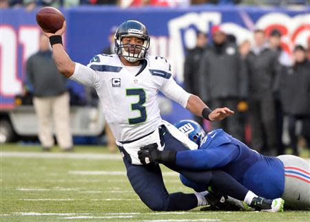 Dec 15, 2013; East Rutherford, NJ, USA; Seattle Seahawks quarterback Russell Wilson (3) throws a pass as he is taken down by New York Giants defensive tackle Linval Joseph (97) in the first half during the game at MetLife Stadium. Mandatory Credit: Robert Deutsch-USA TODAY Sports