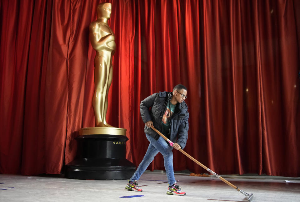 A worker wipes away rainwater from plastic sheeting of the carpet during preparations for Sunday's 95th Academy Awards, Saturday, March 11, 2023, in Los Angeles. (AP Photo/John Locher)