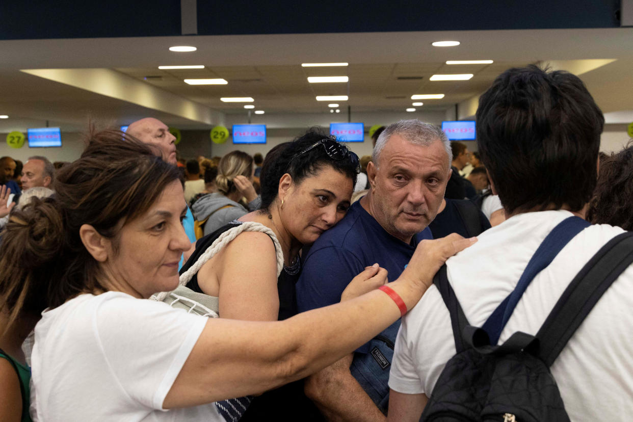 Anna Maria and Lucio, from Naples, Italy, line up at check-in counters as they wait for departing planes at the airport, after being evacuated following a wildfire on the island of Rhodes, Greece, July 24, 2023. REUTERS/Nicolas Economou