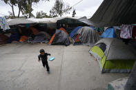 A boy from Honduras runs past tents set up at a shelter for migrants Friday, May 20, 2022, in Tijuana, Mexico. (AP Photo/Gregory Bull)