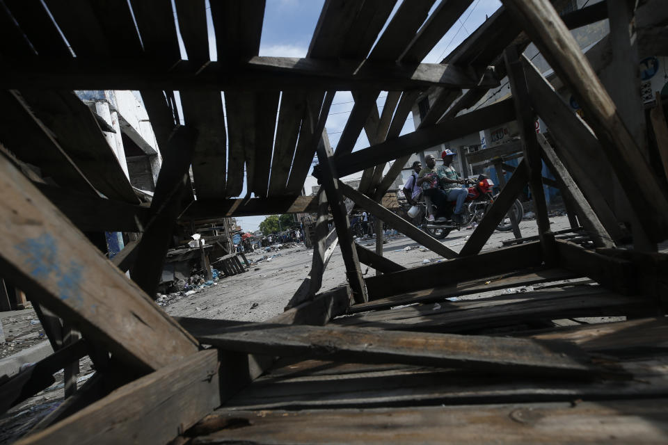 Men on a motorcycle navigate through roads barricaded by protestors, near a market in central Port-au-Prince, Haiti, Wednesday, Oct. 2, 2019. Despite threats of another protest Wednesday amidst anger over corruption, spiraling inflation and dwindling supplies of food and gasoline, residents of Haiti's capital were out on the streets Wednesday morning going about their daily lives as best they could. (AP Photo/Rebecca Blackwell)