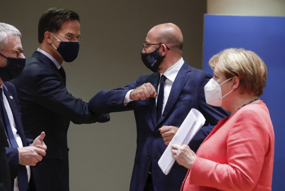 Dutch Prime Minister Mark Rutte, center left, elbow bumps with European Council President Charles Michel, center right, as German Chancellor Angela Merkel, right, walks by during a round table meeting at an EU summit in Brussels, Tuesday, July 21, 2020. Weary European Union leaders are expressing cautious optimism that a deal is in sight as they moved into their fifth day of wrangling over an unprecedented budget and coronavirus recovery fund. (Stephanie Lecocq, Pool Photo via AP)