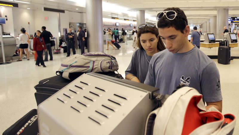 Pablo Monteiro, right, and his sister Pamela check in as they prepare to travel to the Bahamas at Miami International Airport for the Memorial Day weekend in Miami, Saturday, May 25, 2013.