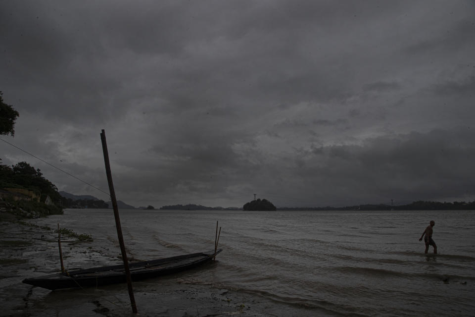 An Indian fisherman walks in the middle of heavy wind and rain in the river Brahmaputra in Gauhati, India, Thursday, May 21, 2020. A powerful cyclone ripped through densely populated coastal India and Bangladesh, blowing off roofs and whipping up waves that swallowed embankments and bridges and left entire villages without access to fresh water, electricity and communications. (AP Photo/Anupam Nath)