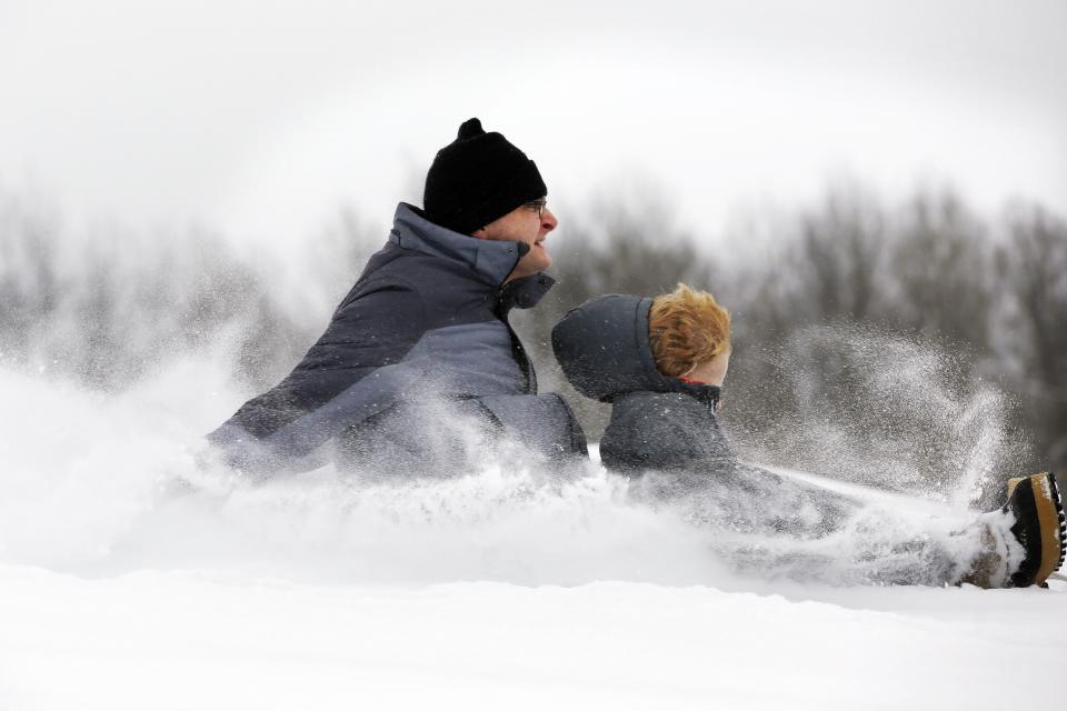 Todd Clark and his son, Sawyer, 4, feel the snow in their faces during their first sledding of the season at Reid Middle School -in Pittsfield, Mass., on Saturday, Dec. 17, 2016. A winter storm of snow, freezing rain and bone-chilling temperatures hit the nations' mid-section and East Coast on Saturday. (Stephanie Zollshan/The Berkshire Eagle via AP)