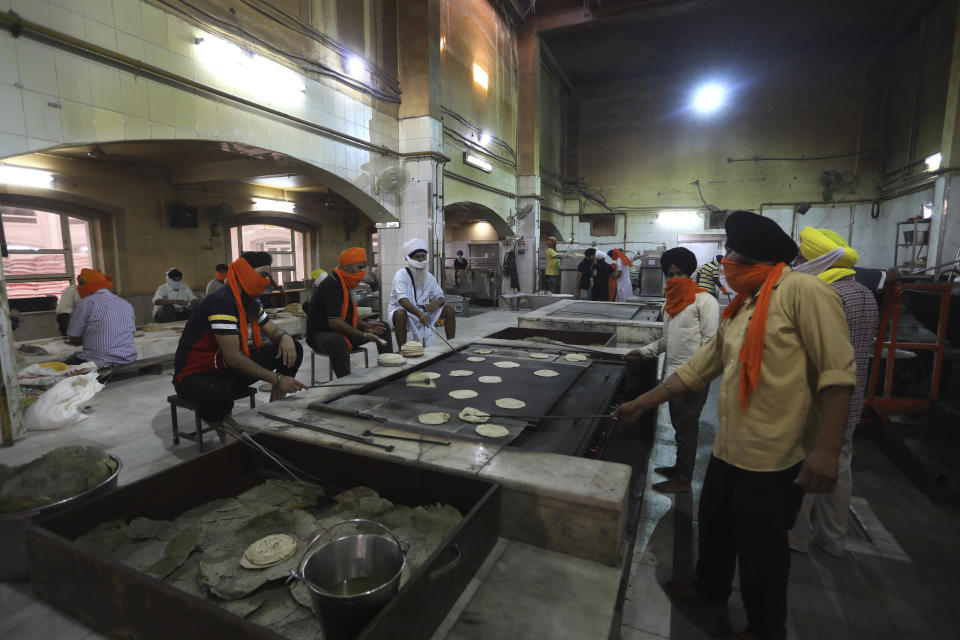 Sikh volunteers make chapatis, thin unleavened breads, in the kitchen hall of the Bangla Sahib Gurdwara in New Delhi, India, Sunday, May 10, 2020. The Bangla Sahib Gurdwara has remained open through wars and plagues, serving thousands of people simple vegetarian food. During India's ongoing coronavirus lockdown about four dozen men have kept the temple's kitchen open, cooking up to 100,000 meals a day that the New Delhi government distributes at shelters and drop-off points throughout the city. (AP Photo/Manish Swarup)