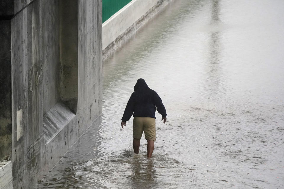 Semi-truck driver Steven Virgil walks into flood waters covering a closed highway to check the depth before trying to drive his truck through in Dallas, Monday, Aug. 22, 2022. Virgil decided to not drive across the water. (AP Photo/LM Otero)