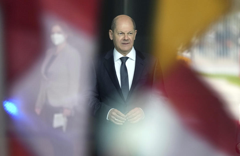 In this picture taken trough a window, German Chancellor Olaf Scholz waits for the arrival of Austria's Chancellor Karl Nehammer at the chancellery in Berlin, Germany, Thursday, March 31, 2022. (AP Photo/Michael Sohn)