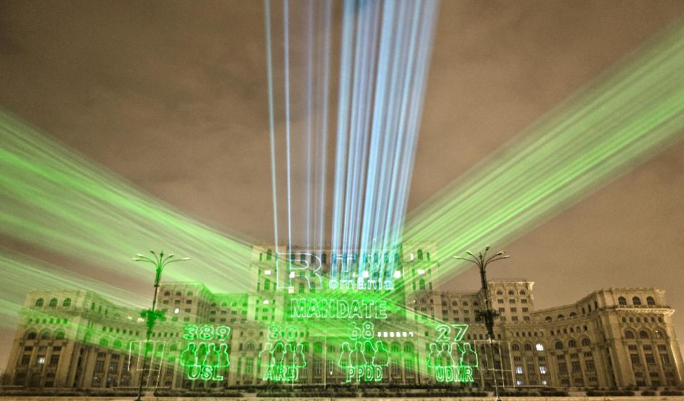 FILE - A picture taken on Dec. 10, 2012, shows lasers projecting the results in Romania's parliamentary elections on the facade of the Parliament Palace in Bucharest, Romania. Twenty-three years after communism collapsed, the Palace of the Parliament, a gargantuan Stalinist symbol and the most concrete legacy of ex-dictator Nicolae Ceausescu, has emerged as an unlikely pillar of Romania's nascent democracy. And while it remains one of the most controversial projects of Ceausescu's 25-year rule, albeit one that has gradually found a place in the nation's psyche, it's also now a tourist attraction, visited by tens of thousands of Romanians and foreigners every year. (AP Photo/Vadim Ghirda)