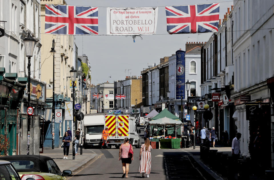 People walk along Portobello Road Market in London, Wednesday, May 27, 2020. Following the gradual easing of the COVID-19 lockdown, street markets will be allowed to reopen in Britain from Monday onwards. (AP Photo/Frank Augstein)