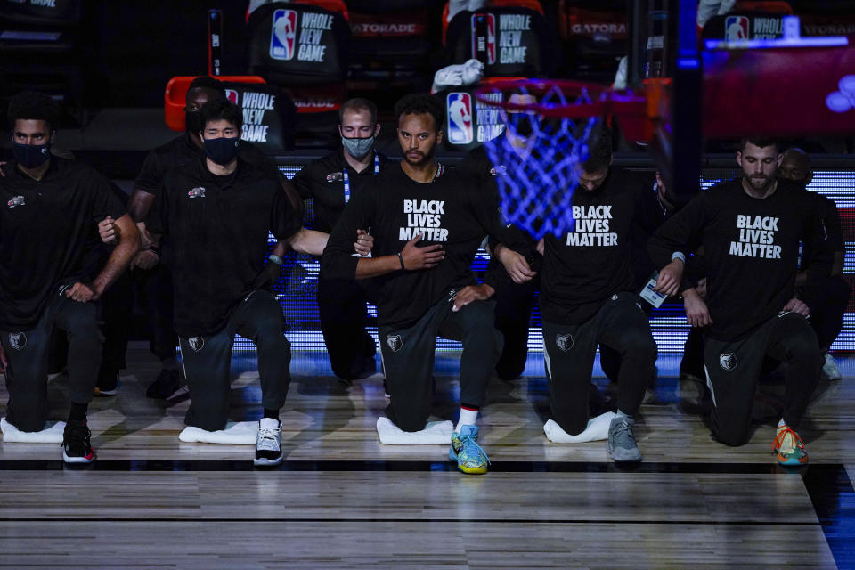 Members of the Memphis Grizzlies kneel for the National Anthem prior the first half of an NBA basketball game against the New Orleans Pelicans Monday, Aug. 3, 2020 in Lake Buena Vista, Fla. (AP Photo/Ashley Landis, Pool)