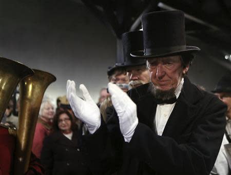 A re-enactor portraying former U.S. President Abraham Lincoln applauds a military band while being welcomed at the Gettysburg, Pennsylvania train station November 18, 2013. REUTERS/Gary Cameron