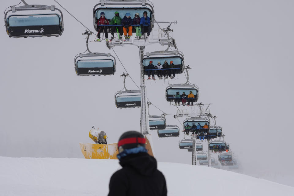 Tourists seated on ski lifts arrive at Plan de Corones ski area, Italy South Tyrol, Saturday, Nov. 27, 2021. After nearly two years of being restricted to watching snow accumulate on distant mountains, Italian skiers are finally returning to the slopes that have been off limits since the first pandemic lockdown in March 2020. But just as the industry is poised to recover from a lost 2020-2021 season after an abrupt closure the previous year, a spike in cases in the Alpine province bordering Austria is underlining just how precarious the situation remains. (AP Photo/Luca Bruno)