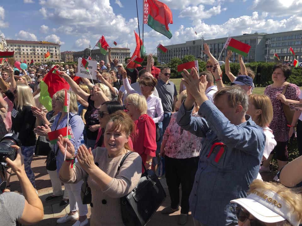 Hundreds supporters of Belarusian President Alexander Lukashenko with Belarusian State flags gather at Independent Square of Minsk, Belarus, Sunday, Aug. 16, 2020. On Saturday, thousands of demonstrators rallied at the spot in Belarus' capital where a protester died in clashes with police, calling for Lukashenko to resign. (AP Photo/Sergei Grits)