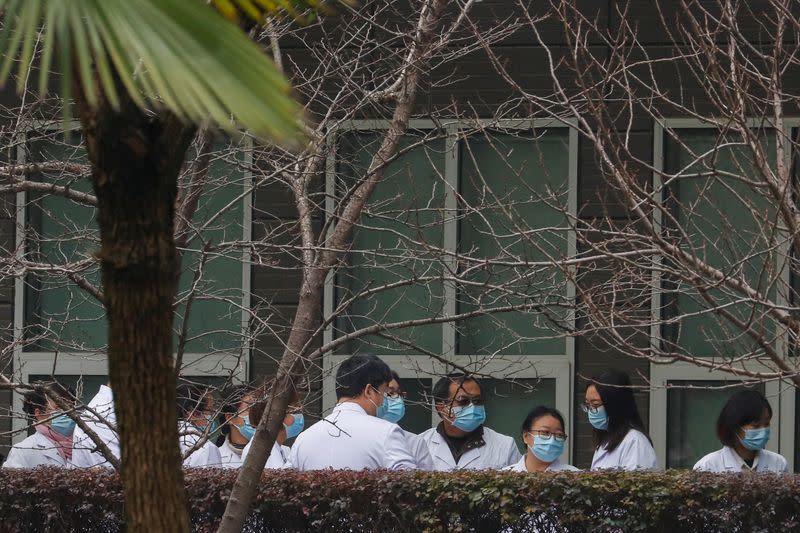 Chinese scientists and officials in lab coats wait at the Hubei Animal Epidemic Disease Prevention and Control Center during a visit of a team of the World Health Organization (WHO), in Wuhan