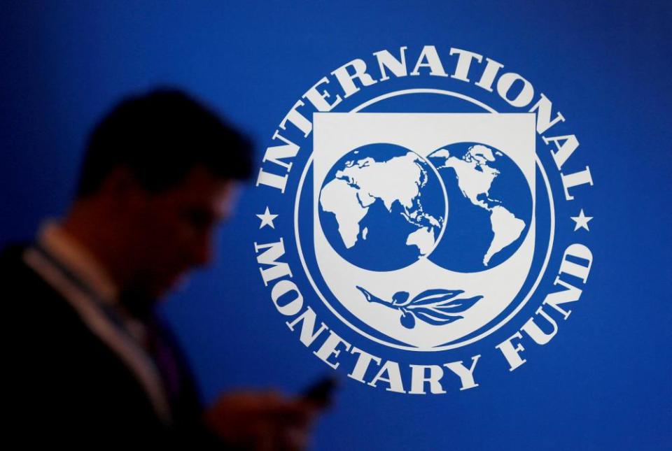 A participant stands near a logo of the IMF