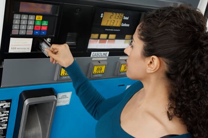 Woman using a credit card to pay at the gas pump.