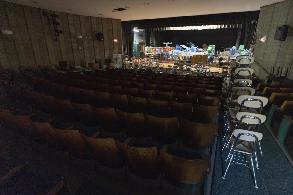 Desks and supplies sit stacked in the auditorium which is being used as storage during the coronavirus outbreak at the Osborn School, Tuesday, Oct. 6, 2020, in Rye, N.Y. (AP Photo/Mary Altaffer)