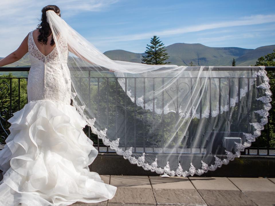 bride with a cathedral veil draped over a fence