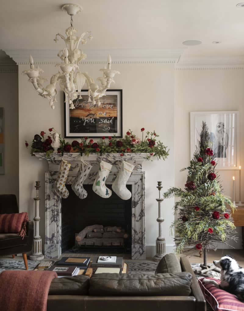 Chandler above a stone fireplace with floral decorations.