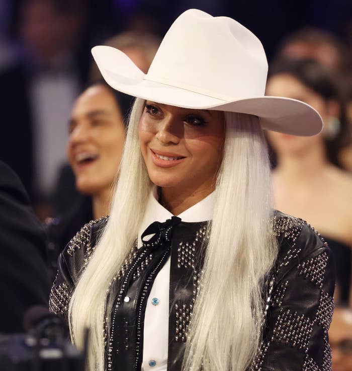 Beyoncé' smiles in a wide-brimmed cowboy hat and embellished dark outfit