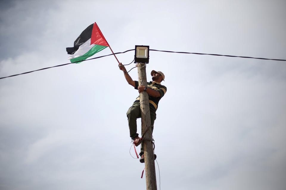 <p>Ein Mann im Gazastreifen befestigt eine palästinensische Flagge an einem Strommasten. (Bild: REUTERS/Ibraheem Abu Mustafa) </p>