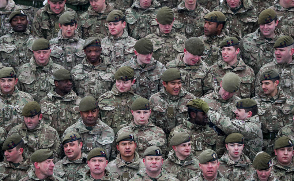 <p>A member of the 1st Battalion Welsh Guards is helped with his beret for a regimental photograph before the combined St David’s Day celebration and pre-deployment service at Elizabeth Barracks, Pirbright, Surrey. (PA) </p>