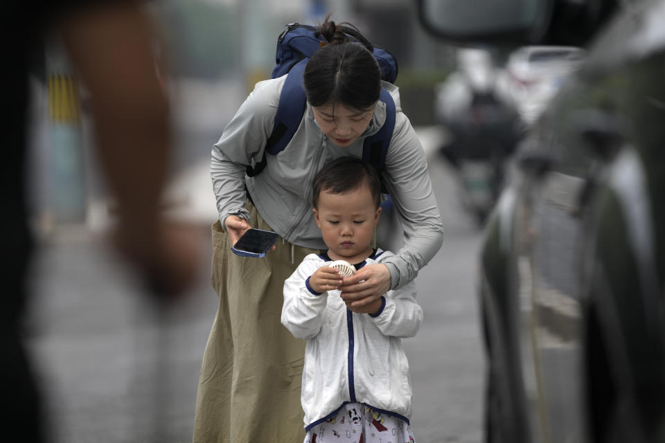 A woman helps a child to switch on an electric fan on a hot day in Beijing, Monday, July 3, 2023. Heavy flooding has displaced thousands of people around China as the capital had a brief respite from sweltering heat. Beijing reported 9.8 straight days when the temperature exceeded 35 C (95 F), the National Climate Center said Monday. (AP Photo/Andy Wong)