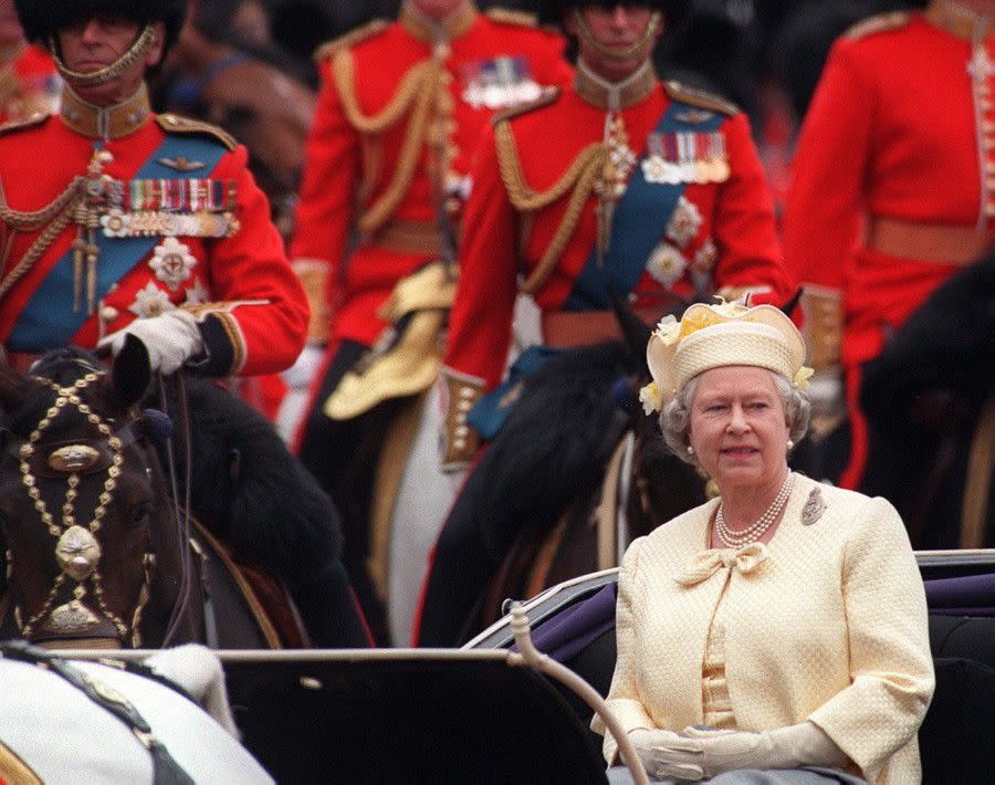 Looking cheerful in yellow, Her Majesty makes her way to Buckingham Palace after watching the Trooping of the Colour in London on June 14, 1997.