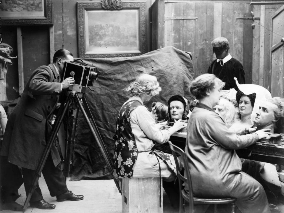 20th March 1928: A cameraman films a couple of women as they craft waxwork heads for a new exhibition at Madame Tussaud's museum in London. (