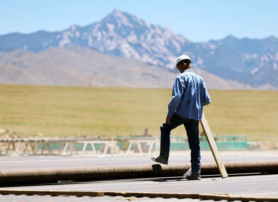 A workers steps over a length of pipe at a drilling rig at the FORGE geothermal demonstration sight near Milford on Thursday, July 6, 2023. | Scott G Winterton, Deseret News